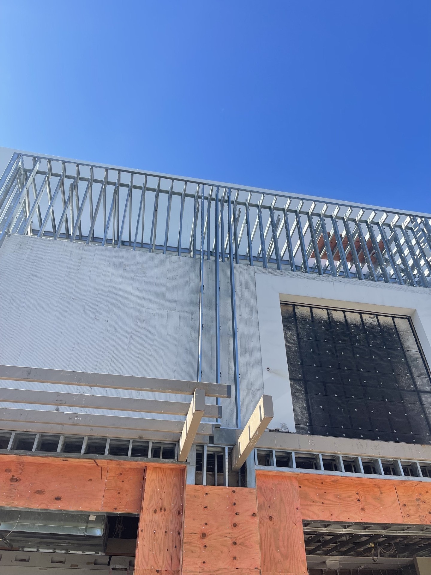 Steel framing and sheathing on commercial building against blue sky