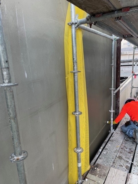 Worker on scaffolding applying stucco finish coat